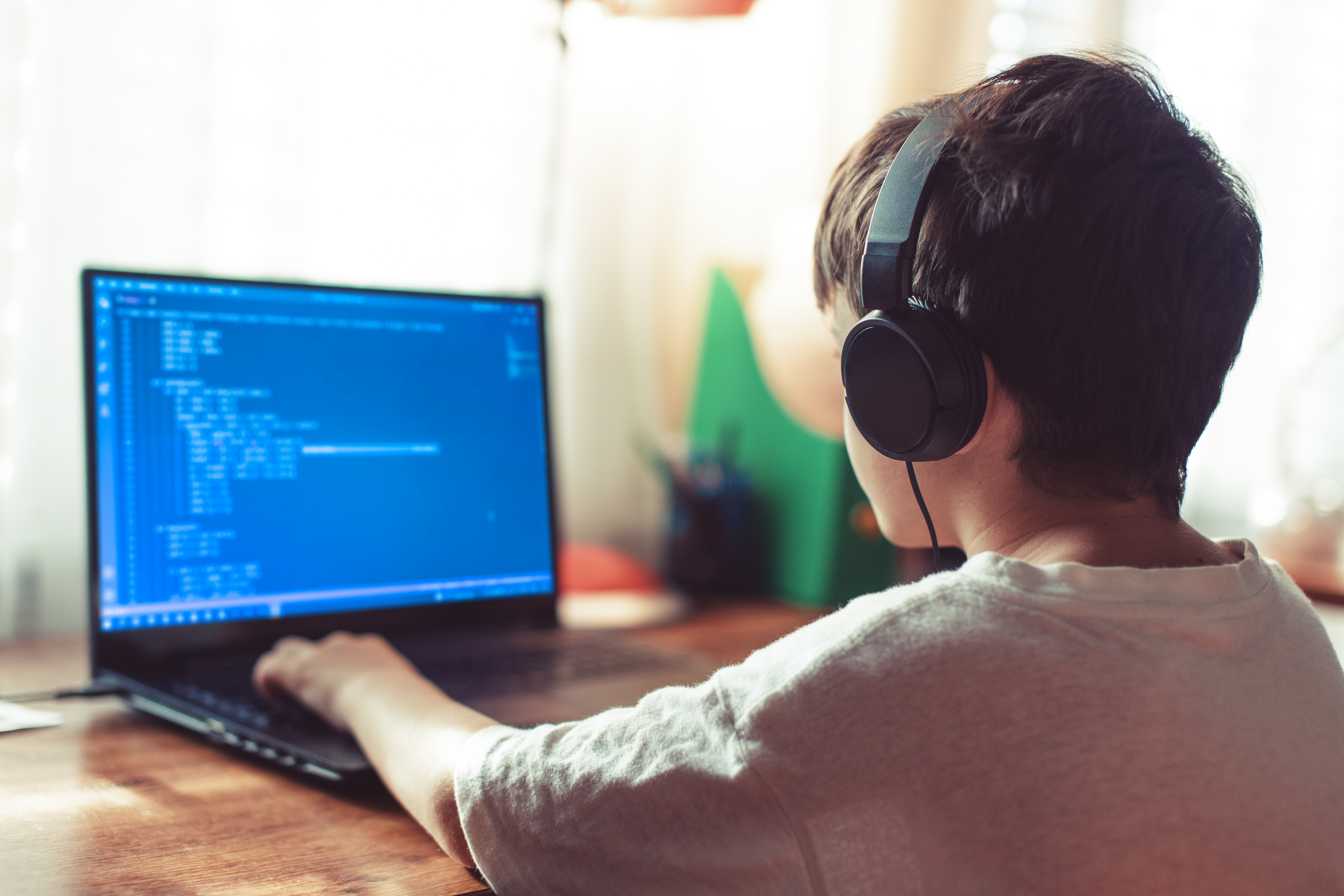boy programming at laptop with headphones